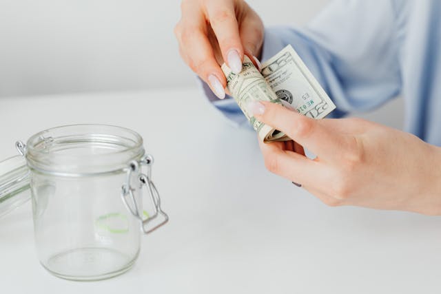 person rolling money to put it in jar