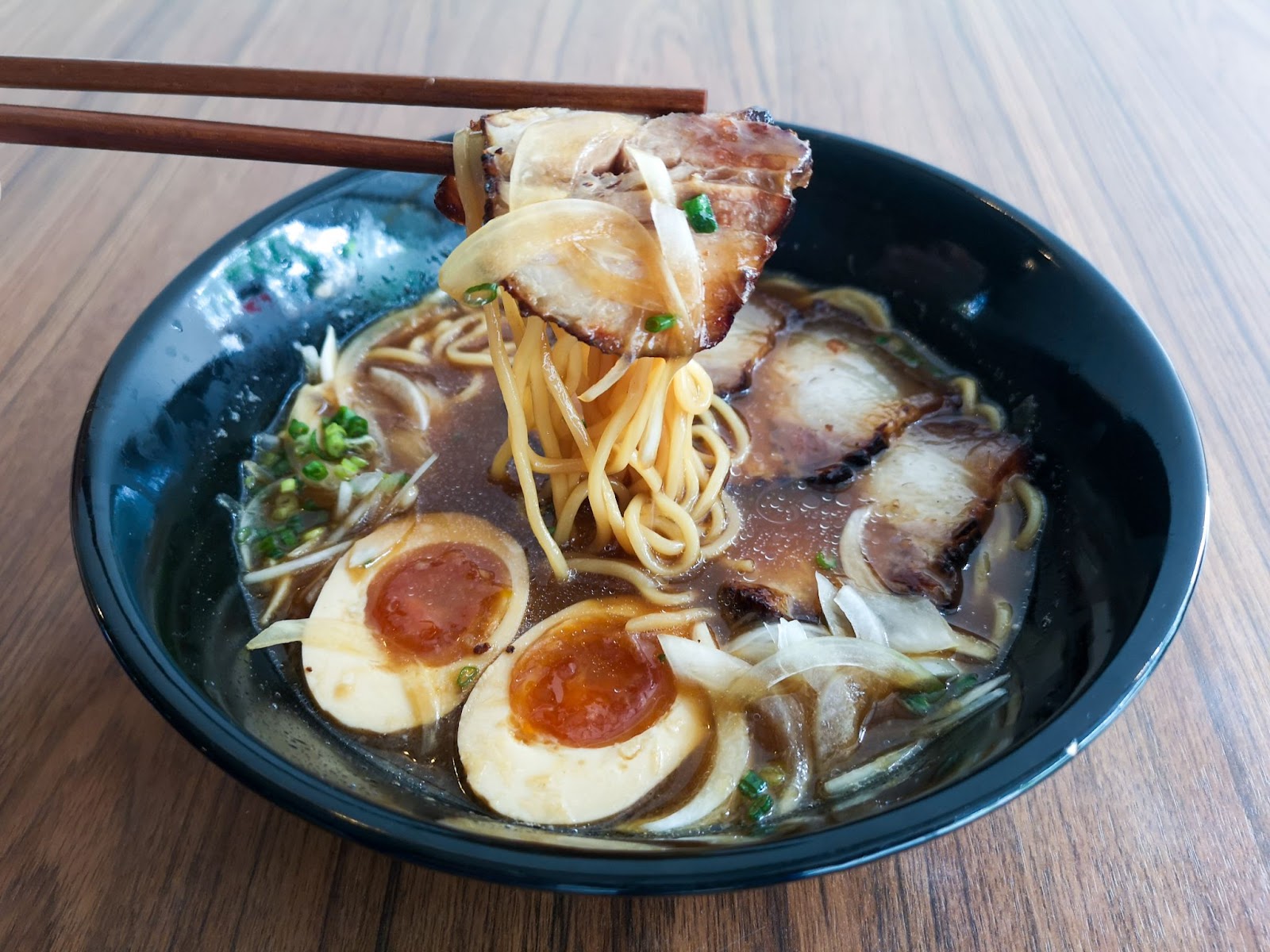 Shoyu ramen in a blue bowl with chopsticks