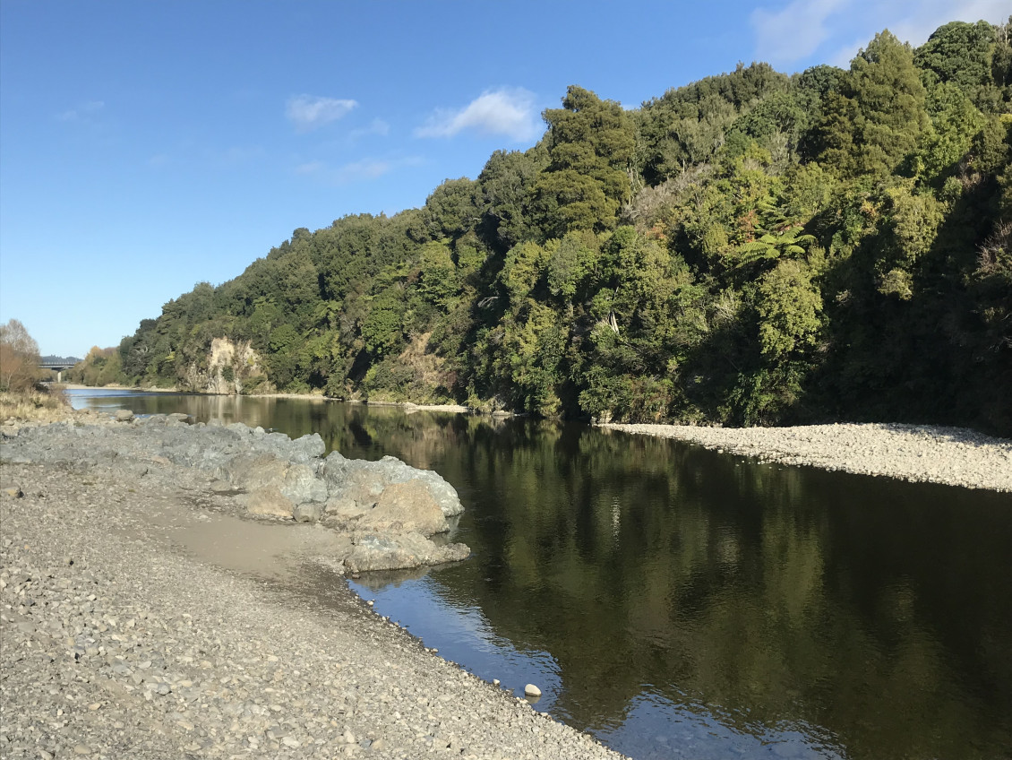 A picture of the Hutt river with a rocky bank on the left and a tree-lined bank on the right