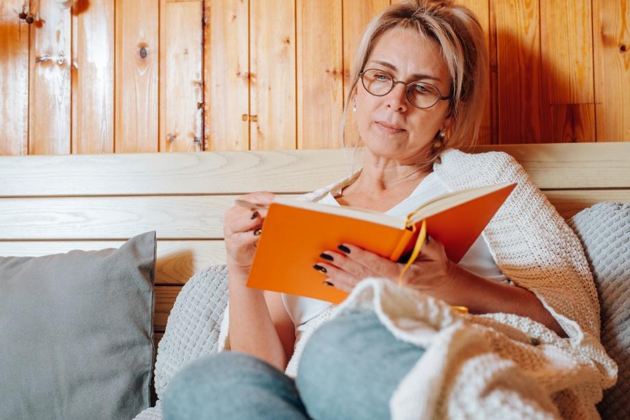 A person sitting on a bed reading a book

Description automatically generated