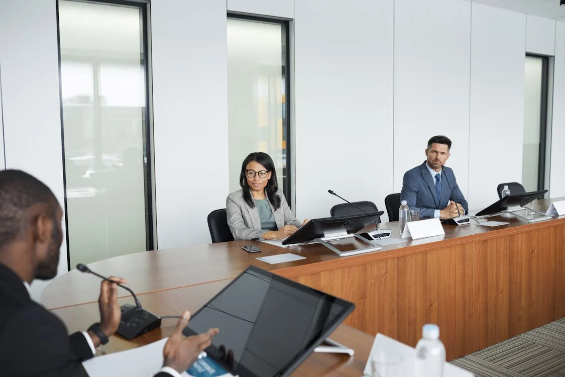 Three people in a conference room during a business meeting.