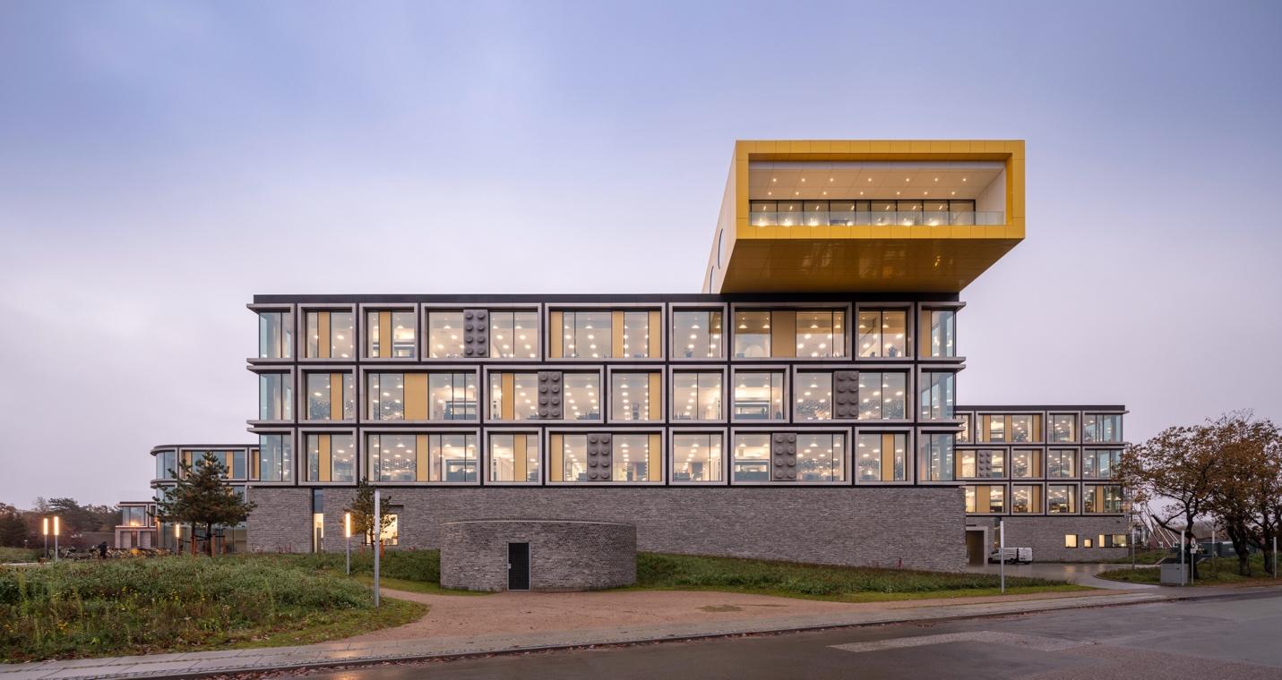 A building with a yellow and grey facade Description automatically generated