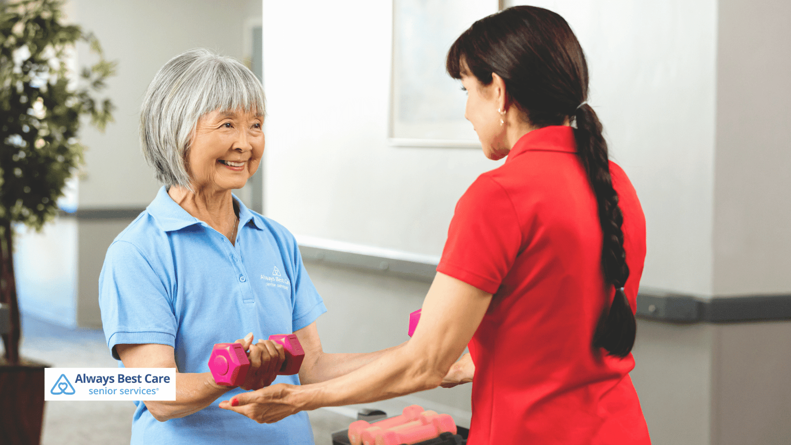 This image depicts a caregiver helping a senior woman exercise