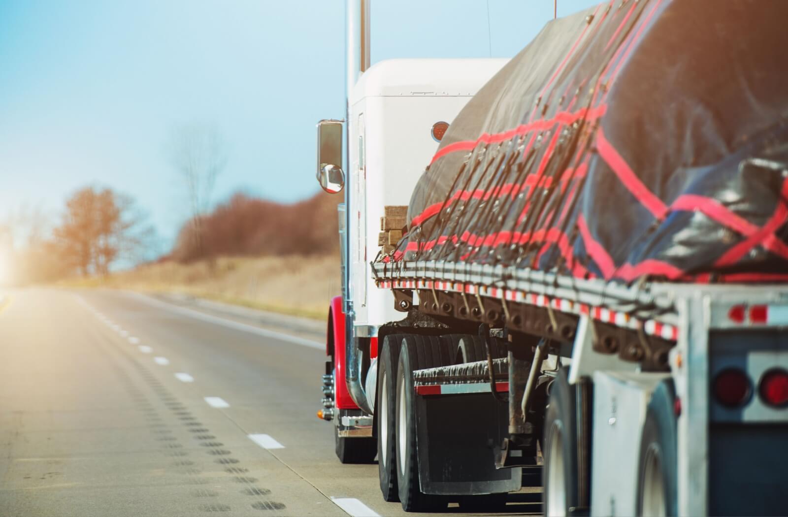 A heavy-duty truck hauls a heavy load down an open highway, putting strain on its engine.