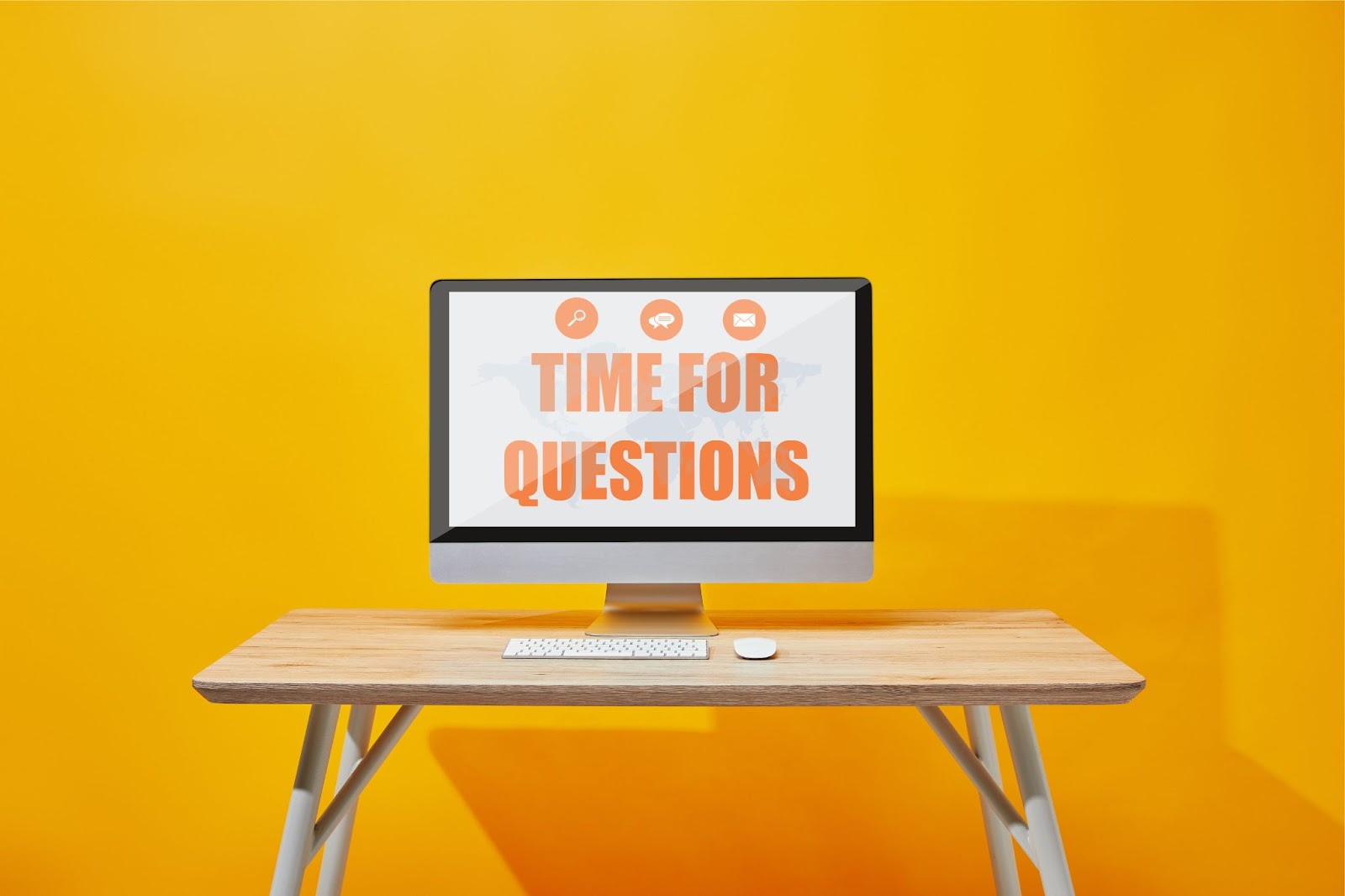 (A computer monitor on a wooden desk displays the text "Time for Questions" against a yellow background.)