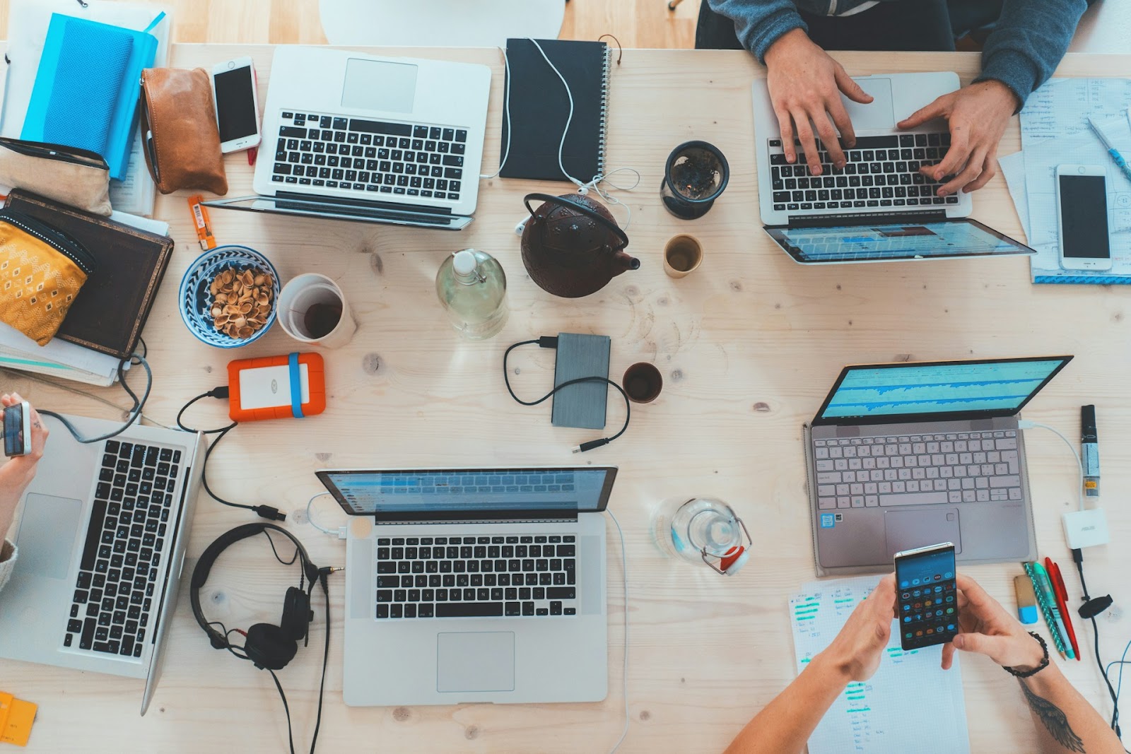 A group of people focused on their laptops, collaborating around a table in a casual workspace setting