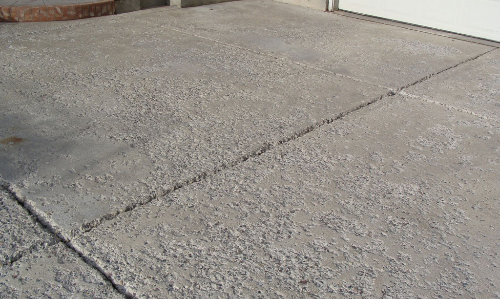 A residential driveway that is spalling or flaking showing signs of concrete damage