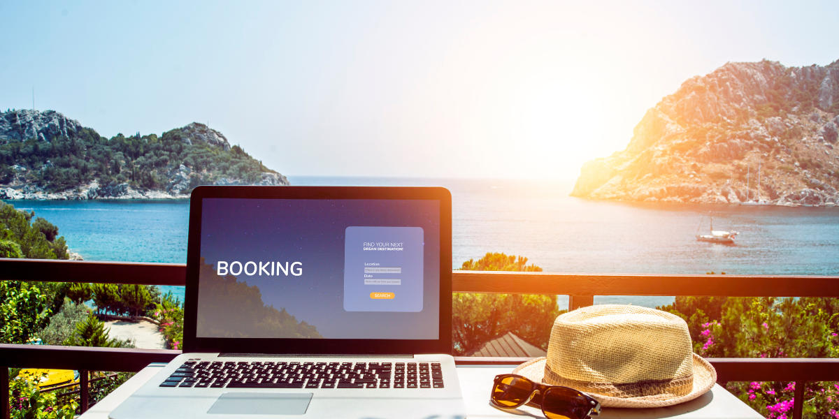 Laptop with the word 'booking' on the screen next to vacation essentials, representing the benefits of the best Airbnb management software.