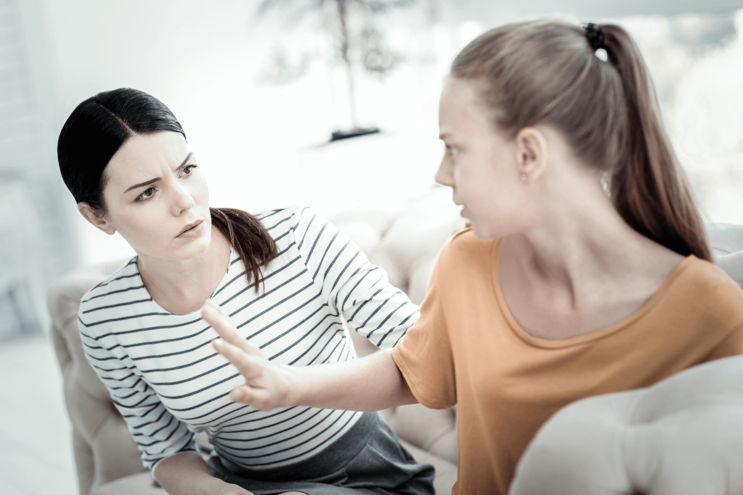 Mother speaking to her daughter who has her hand up in frustration