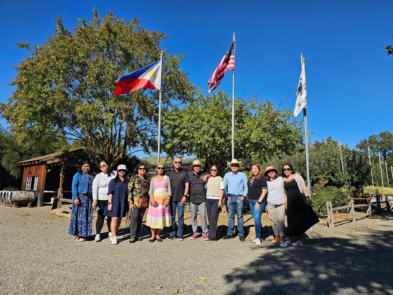 A group of people standing in front of flags

Description automatically generated