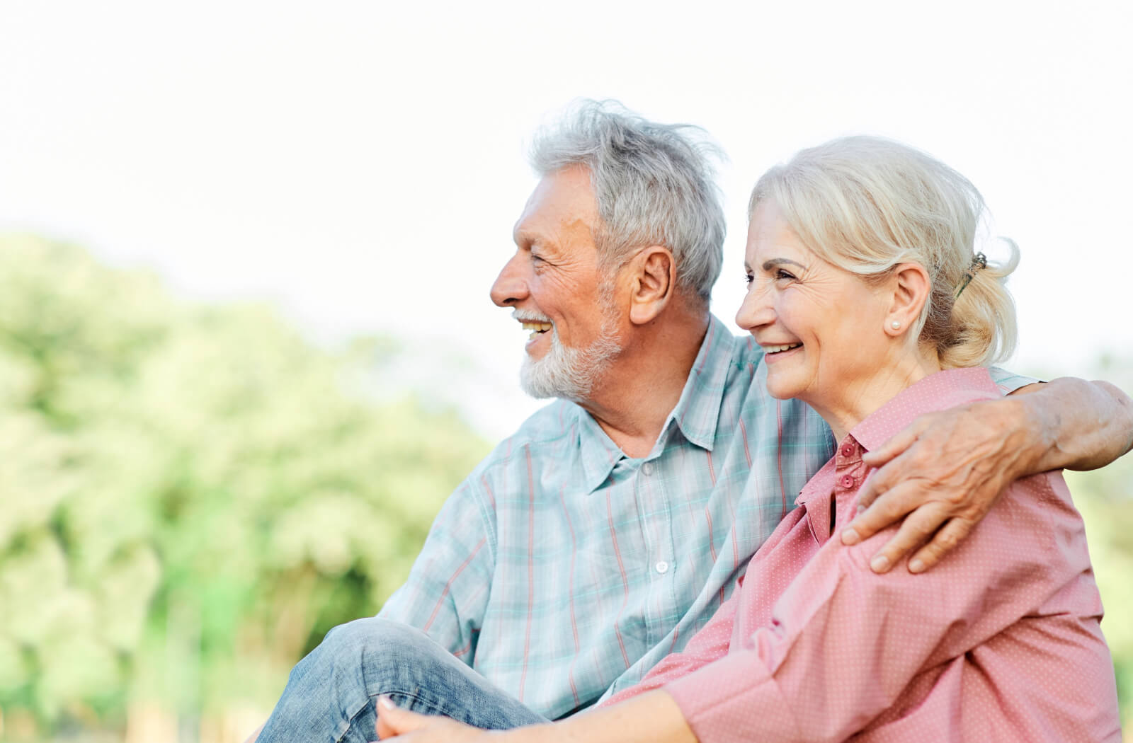 An older couple sitting outside in a park and smiling while on a trip to Nashville.