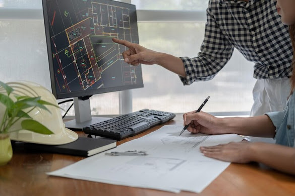 Engineers discuss a blueprint while checking information on a tablet computer in a office