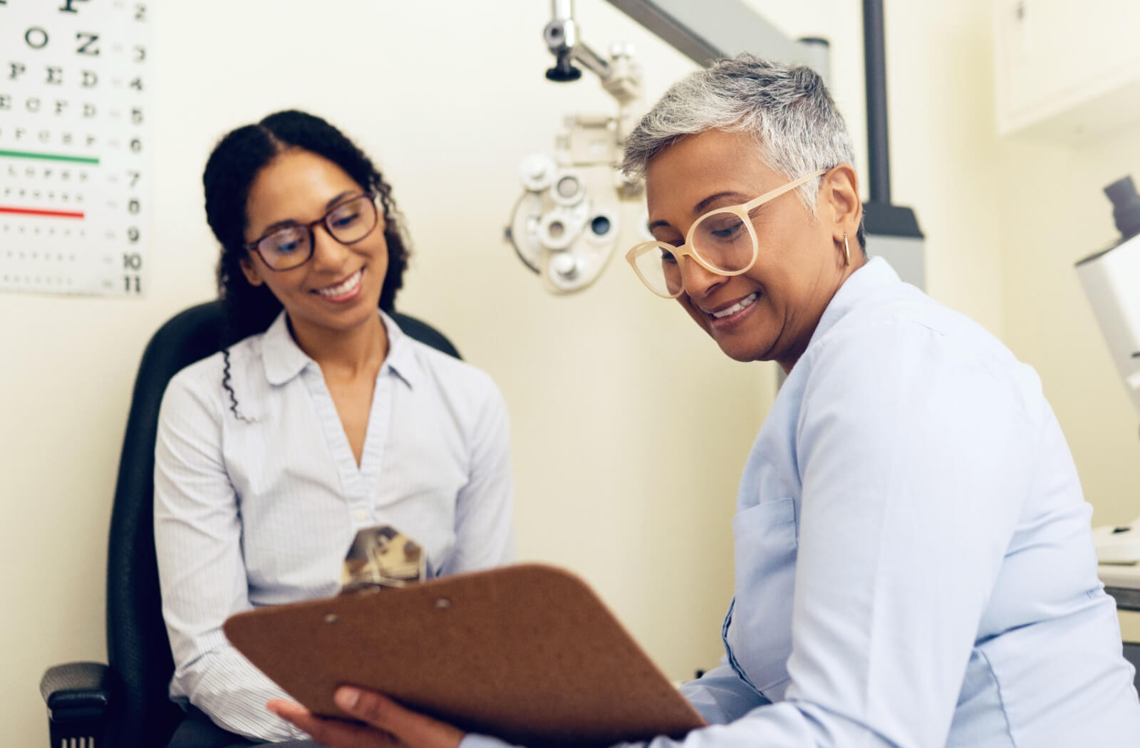 An optometrist and her patient smiling while discussing her Medicaid coverage after an eye.