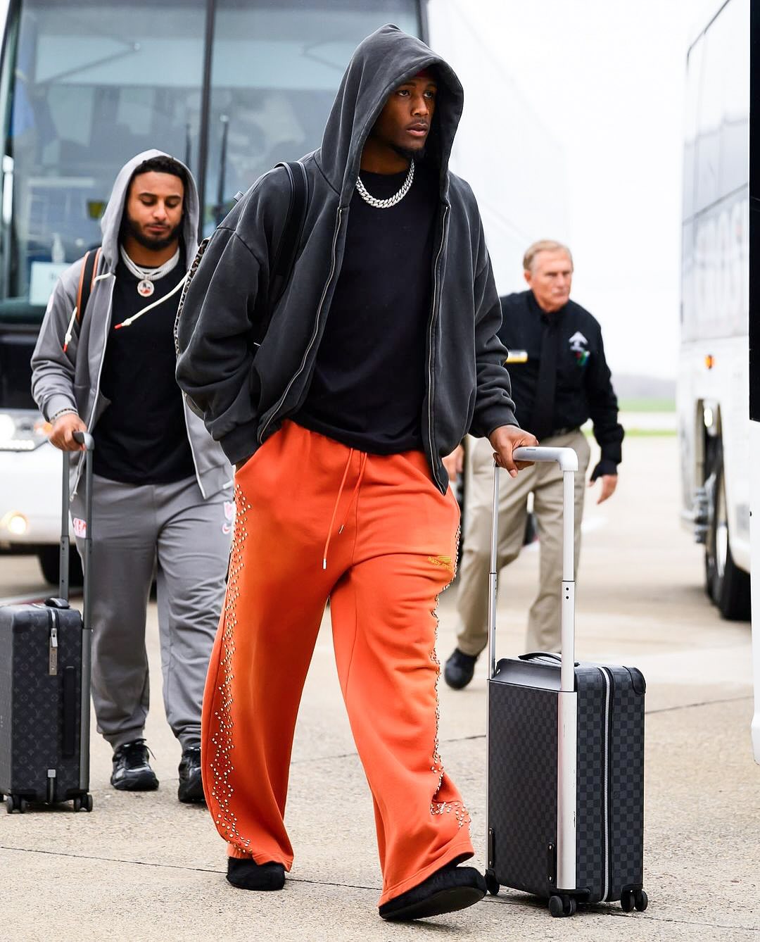 Photo shared by blitzfits on November 16, 2024 tagging @teehiggins, and @bengals. May be an image of 3 people, people playing football, people playing basketball, people standing, suitcase, sweatsuit, sportswear, sweatpants and text.