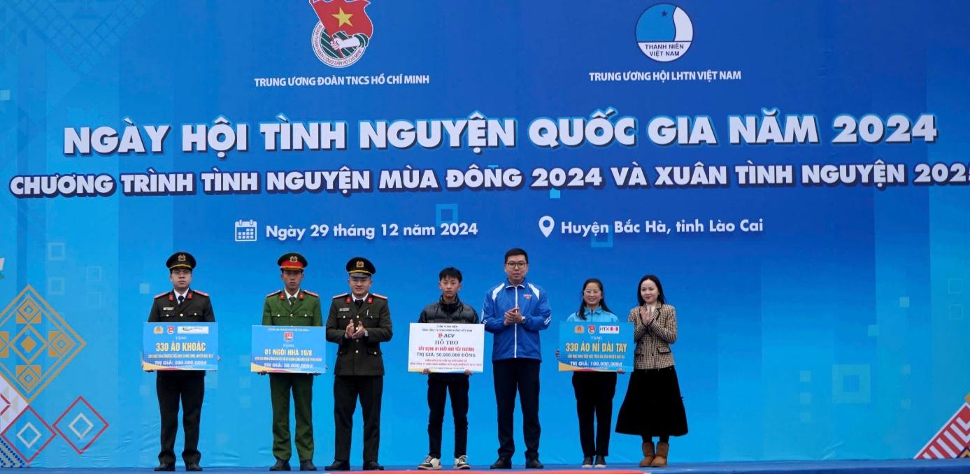 A group of people standing in front of a blue bannerDescription automatically generated