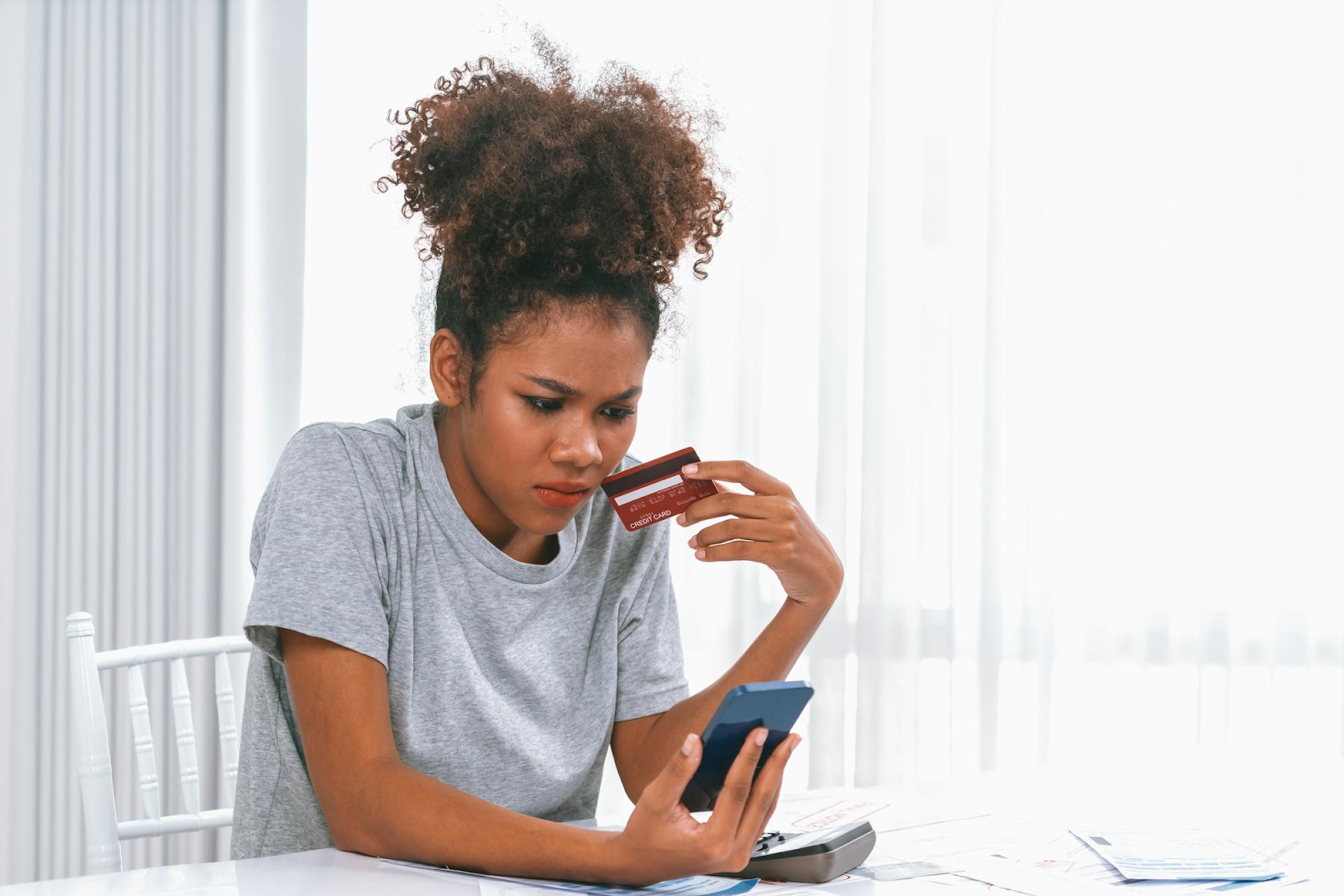 A lady with a credit card on one hand and a phone on another wondering how whether she can still use her thd/cbna card during a dispute
