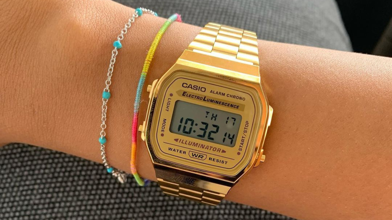 A wrist with a gold watch

Description automatically generated