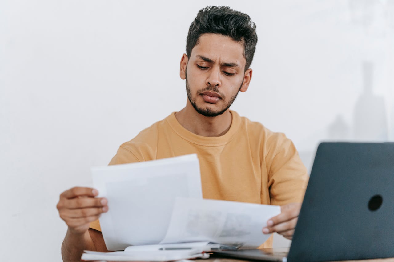 A person reviewing documents with a laptop