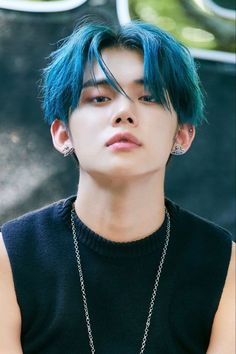 This contain TXT Yeonjun   with blue hair wearing a black shirt and silver chain around his neck