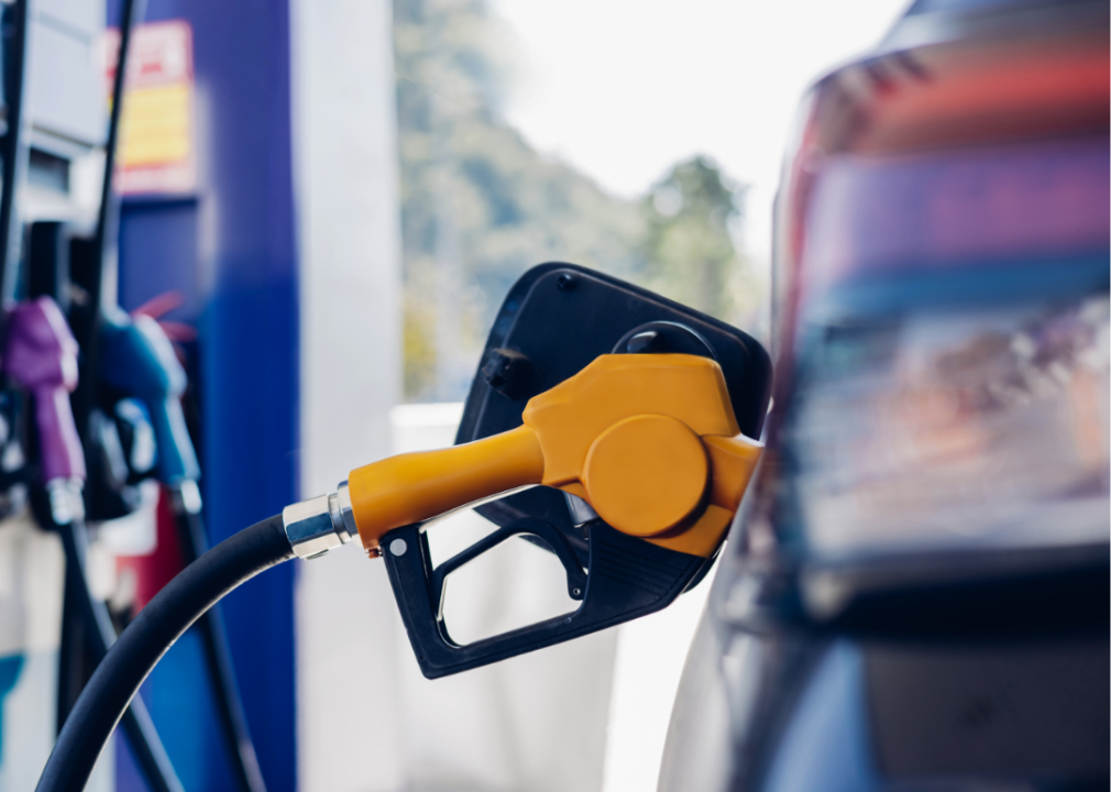 A dark-colored sedan being filled up at a gas station.