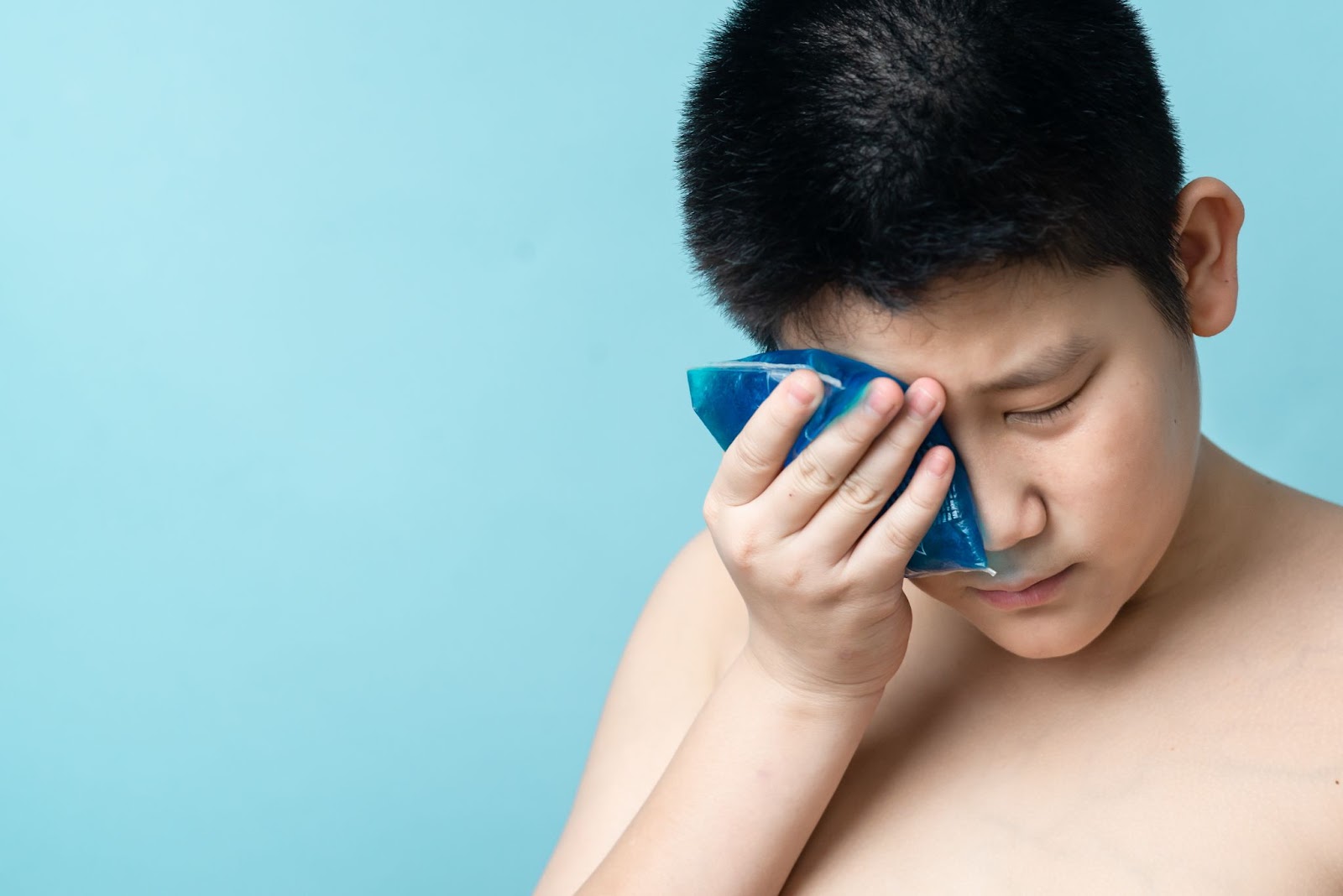 A teenage boy applies a cold compress to help relieve the uncomfortable symptoms of a stye.