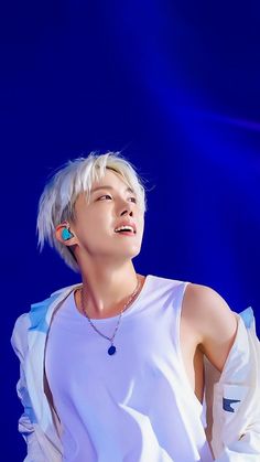 This contains an image of J-Hope 
wearing a white shirt and some necklaces and looking up at the sky