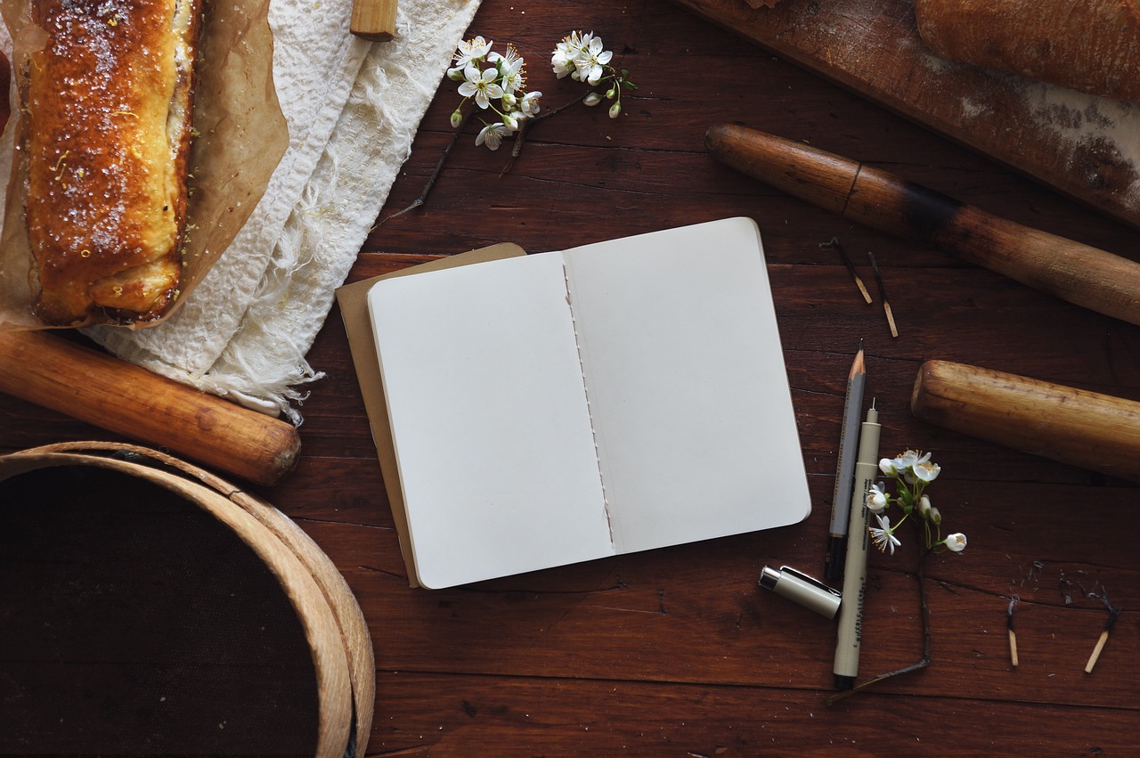 A busy counter with bread, notebook, pencils and pens 