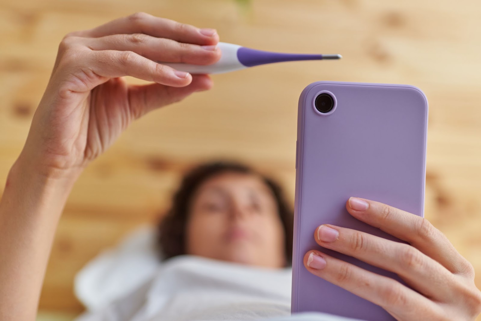 ležiaca žena si na mobile zaznamenáva meranie bazálnej teploty