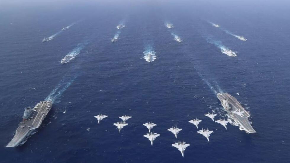 在南中国海某处，歼-15编队飞越解放军海军辽宁舰、山东舰航母编队。