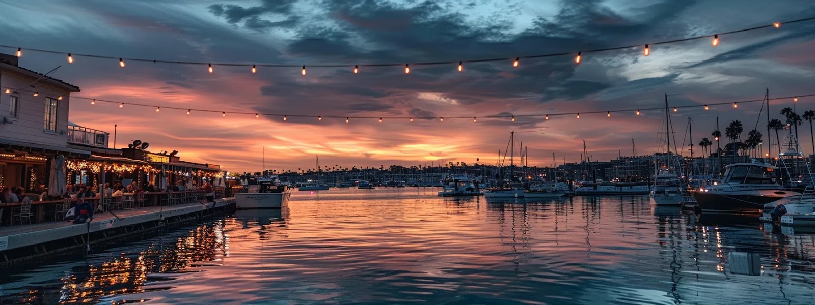 a serene sunset over newport beach harbor with docked duffy and pontoon boats, reflecting in the calm waters, as diners enjoy waterfront dining under string lights.