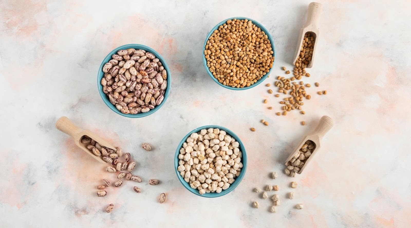 Vue de dessus des haricots, des pâtes et des pois chiches dans des bols sur fond blanc