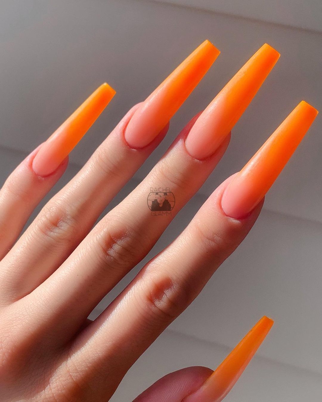 Close up of nails with glittery orange nails having Long Orange Talons