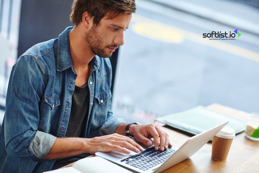 Man working on a laptop with a cup of coffee beside him.