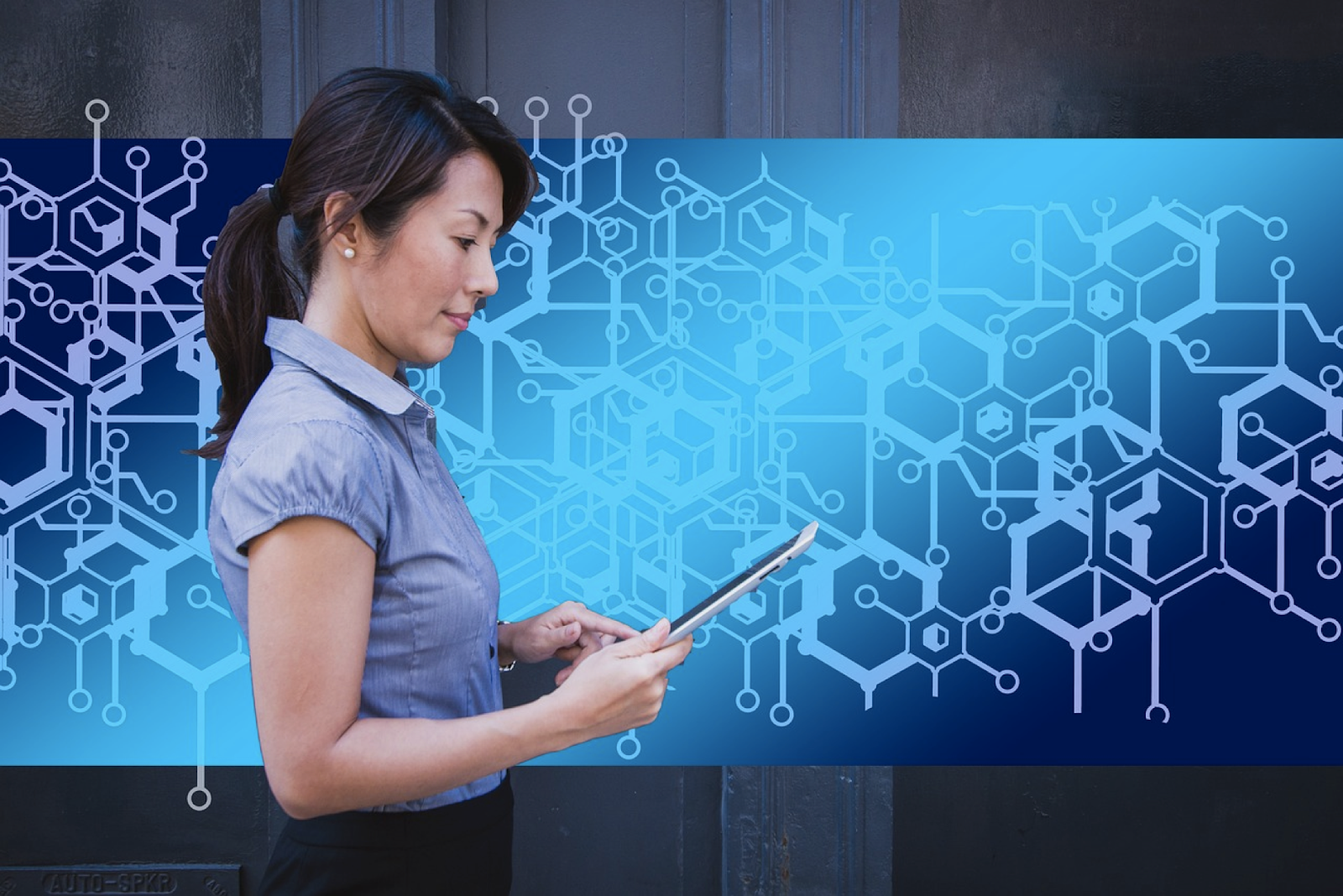 Woman holding a tablet, standing in front of digital hexagonal patterns.