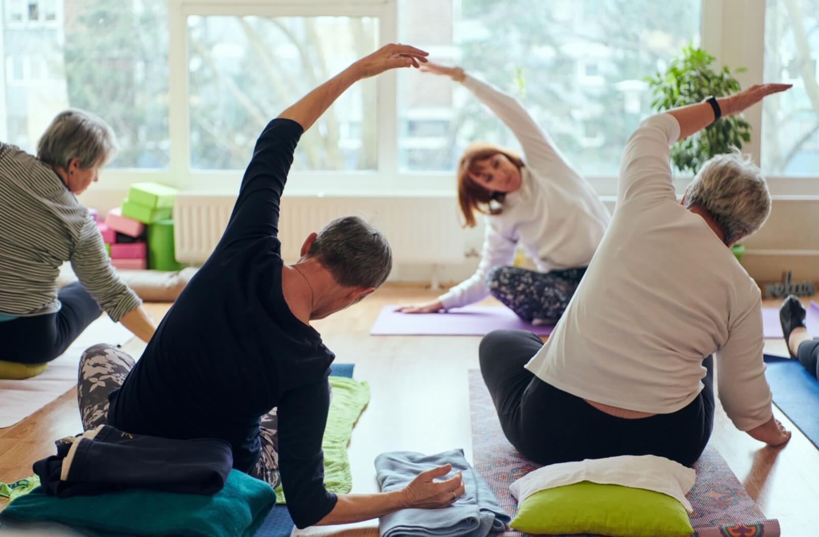  Several seniors gather in a circle, stretching in yoga poses together as part of a community health initiative