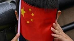 上海外滩的一个小男孩手拿一面中国国旗参加庆祝中共建政75周年的活动。(2024年10月1日)
