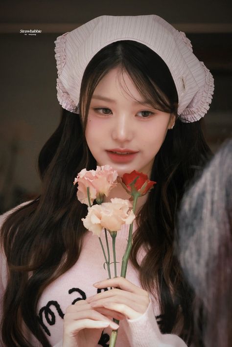 This contains an image of Jang Wonyoung holding a flower