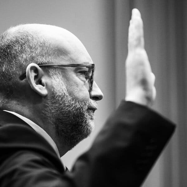 A black-and-white picture of Russ Vought’s side profile as he raises his right hand.