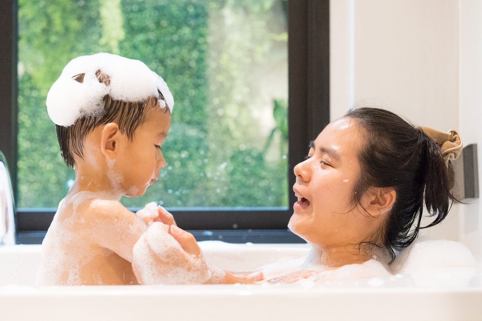 Une maman partage un bain moussant avec son jeune fils.