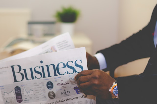 Person wearing suit reading business newspaper. Photo by Adeolu Eletu.