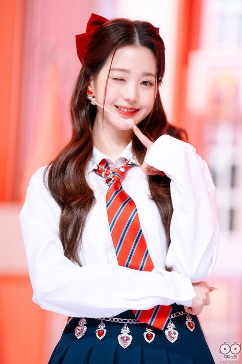 This contains a picture of Wonyoung  in a school uniform posing for the camera with her hand on her chin