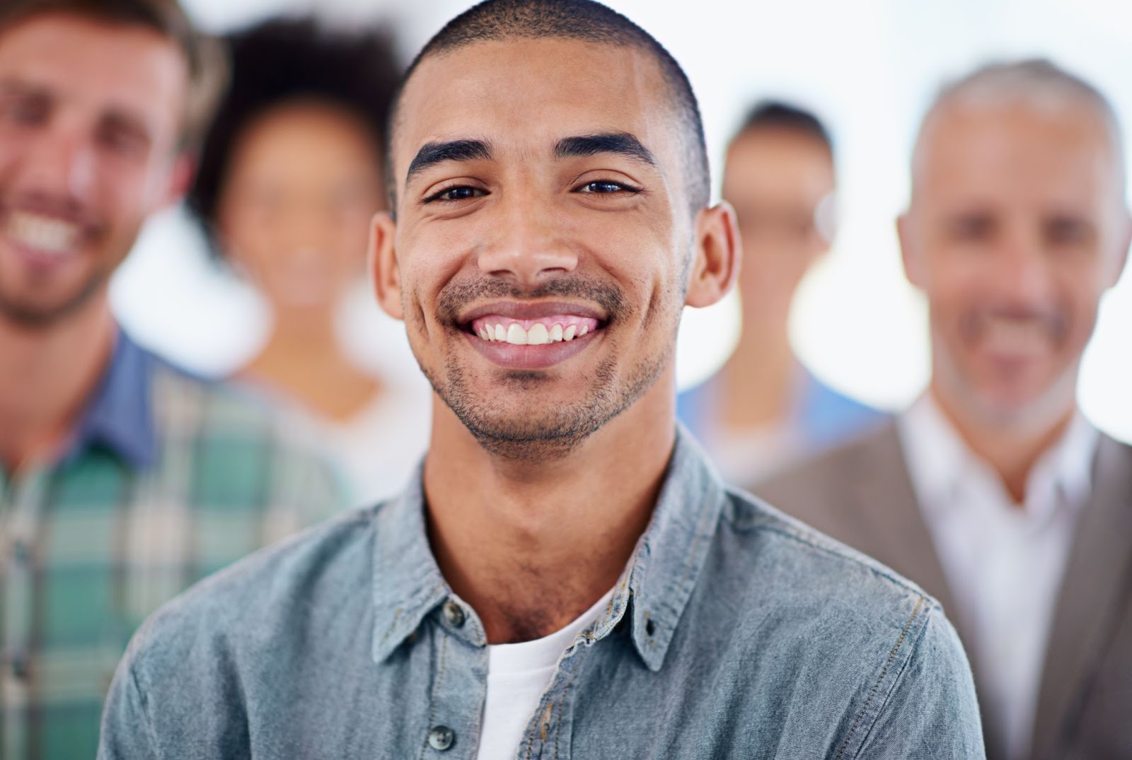 Smiling man with 4 people blurred in the background. 