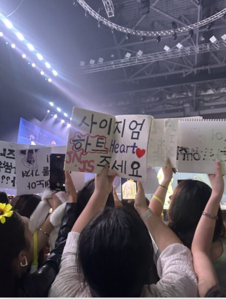 A picture of fans holding sketchbook in a concert