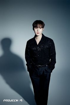 This contains an image of  Ha Sungwoon standing in front of a wall with his shadow on the wall behind him