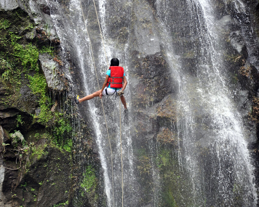 A man doing waterfall rappelling.