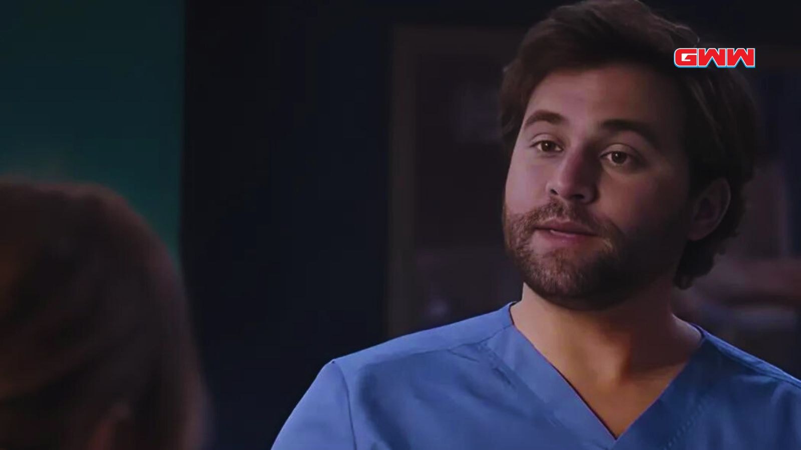 Lucas Adams in medical attire talking to a colleague in Grey's Anatomy