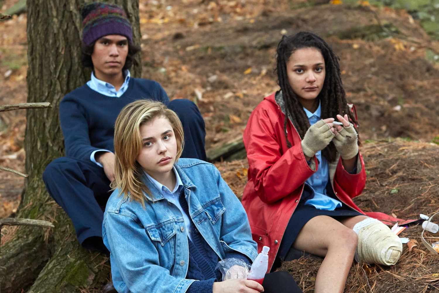 Tres jóvenes sentados en un bosque con expresiones pensativas en la película The Miseducation of Cameron Post.