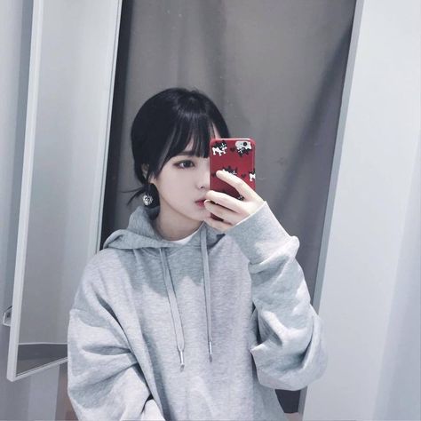 This contain an image of a netizen holding a phone and putting on a gray color hoodie