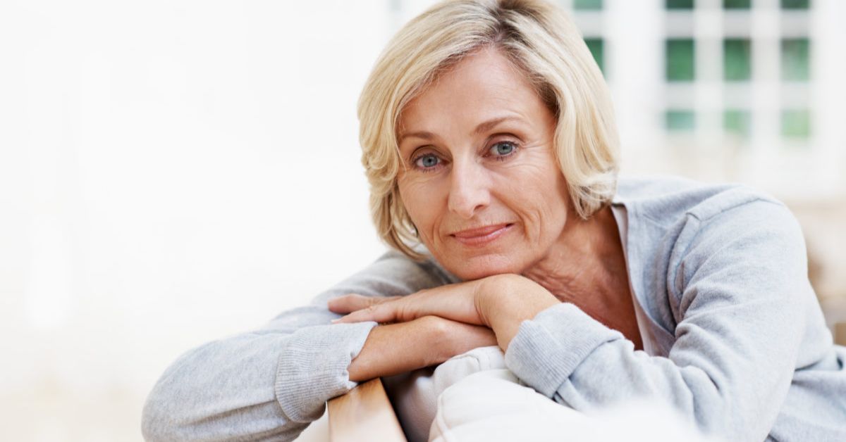 A woman with an Angled Bob hairstyle leans on a couch, arms crossed, exuding confidence and relaxation.