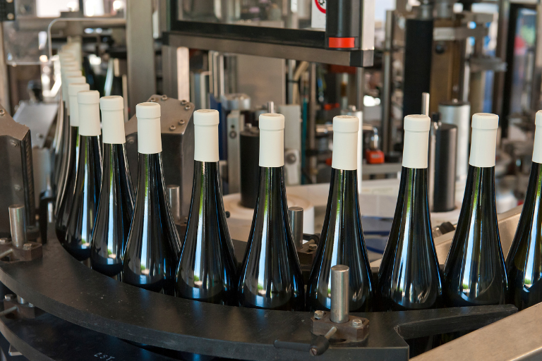 Botellas de vino en línea de embotellado automatizada en bodega moderna, tecnología para la producción eficiente de vinos de calidad en Canarias.